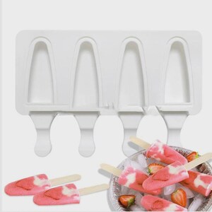 May include: White silicone popsicle mold with four cavities, and several strawberry and cream popsicles on wooden sticks. The popsicles are pink and white, and some have fresh strawberry slices.