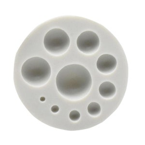 May include: A white silicone mold with 10 round cavities of varying sizes. The mold is designed for making small round shapes, such as candies, chocolates, or soap.