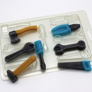 Könnte beinhalten: Eine transparente Plastikform mit acht verschiedenen Werkzeugformen zum Herstellen von Süßigkeiten oder Schokolade. Die Werkzeuge umfassen einen Hammer, einen Schraubenschlüssel, einen Schraubendreher, eine Zange, eine Säge und zwei Schraubenschlüssel in verschiedenen Größen.