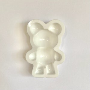 May include: White silicone mold shaped like a standing teddy bear. The mold has a smooth surface and is designed for making small resin crafts.