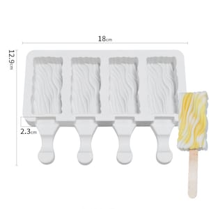 May include: White silicone popsicle mold with four individual molds, each with a wavy texture and a stick holder. The mold measures 18 cm long, 12.9 cm wide, and 2.3 cm high.