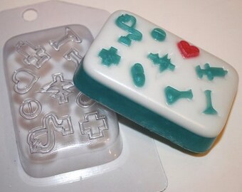 May include: A clear plastic mold with various symbols and a teal green soap bar with the same symbols. The soap bar has a red heart symbol.