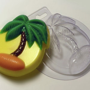 Könnte beinhalten: Eine transparente Plastikform zum Herstellen von Seife oder Kerzen in Form einer Palme. Die Form ist mit einem fertigen Seifenstück darin gezeigt, das eine grüne Palme mit braunem Stamm und einem gelben Strand zeigt.