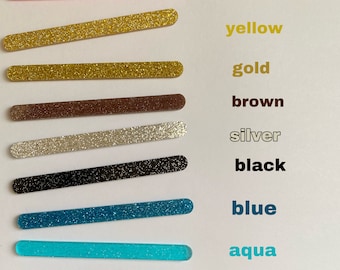 May include: Nine glitter-covered craft sticks in various colours, including pink, yellow, gold, brown, silver, black, blue, aqua, and grey.