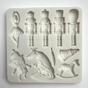 May include: A white silicone mold featuring designs from The Nutcracker ballet. The mold includes a ballerina, nutcracker soldiers, a rat king, a rocking horse, and other festive shapes. Ideal for crafting themed decorations.