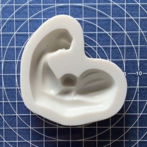 May include: White silicone mold shaped like a heart with a raised design of a sleeping baby inside.