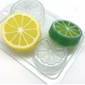 May include: A clear plastic mould with three cavities shaped like lemon and lime slices. The mould is filled with yellow lemon and green lime soap slices.
