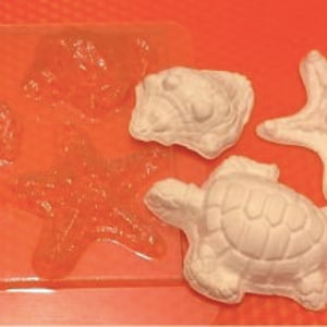 May include: A clear plastic mold with four cavities for making resin crafts. The mold features two turtle designs, a starfish, and a seahorse. The mold is filled with white resin, showing the finished product.