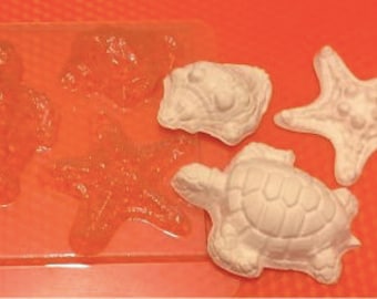 May include: A clear plastic mold with four cavities for making resin crafts. The mold features two turtle designs, a starfish, and a seahorse. The mold is filled with white resin, showing the finished product.