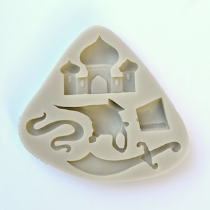 May include: A silicone mold for baking, featuring a design of a mosque, a genie, a scimitar, and a turban. The mold is light gray and has a triangular shape.