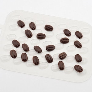 May include: A clear plastic tray with a grid pattern filled with chocolate brown coffee beans.