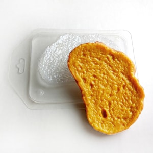 Op de afbeelding: Een gele siliconen mal in de vorm van een snee brood. De mal is gemaakt van siliconen van voedselkwaliteit en is ontworpen om realistisch uitziend brood te maken voor knutselen of decoratie.