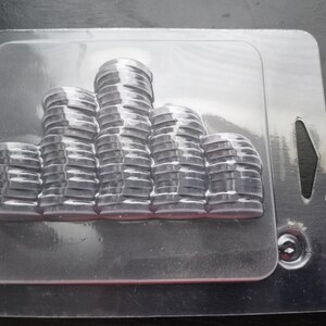 May include: A clear plastic packaging tray with a row of black rubber rings stacked in a pyramid shape.