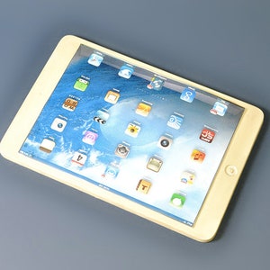 May include: A white tablet computer with a blue and white screen displaying various app icons. The tablet has a silver border and a home button.