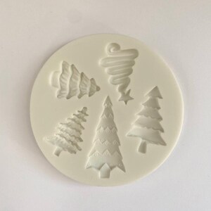 May include: White silicone mold with six Christmas tree designs. The mold features a variety of tree shapes, including a spiral tree, a traditional tree with ornaments, and a simple tree with a star on top.