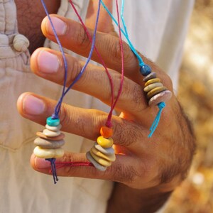 May include: Three necklaces with layered stone beads. The necklaces are made with different colored cords and feature turquoise, orange, and blue beads.
