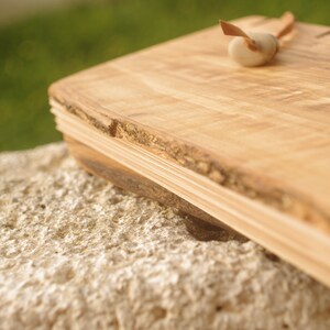May include: A wooden cutting board with a natural edge and a light brown color. The board is made of multiple layers of wood and has a rustic look.