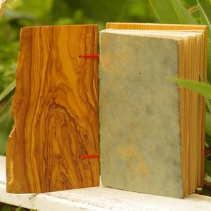 May include: A handmade journal with a wooden cover and a blue paper cover. The journal is bound with red string.