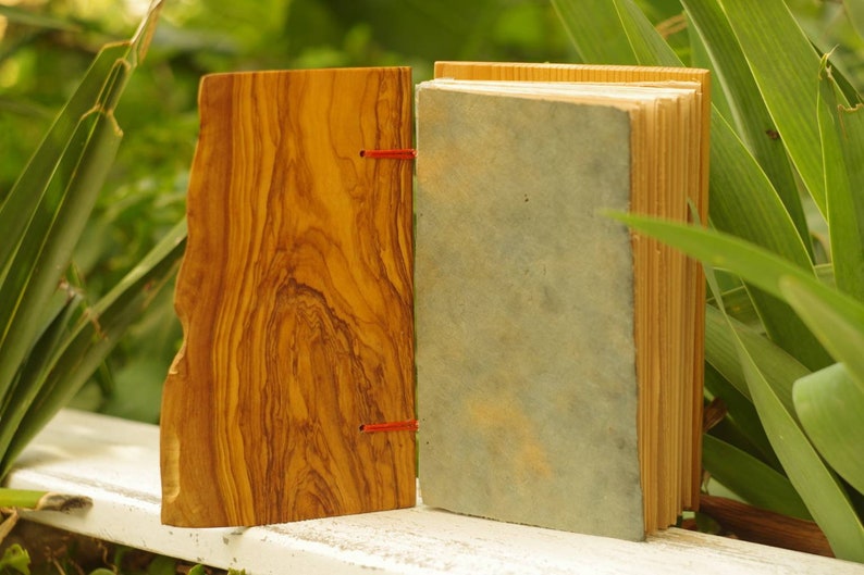 May include: A handmade journal with a wooden cover and a blue paper cover. The journal is bound with red string.