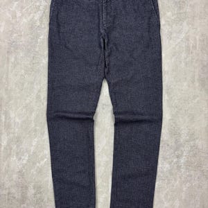 May include: Navy blue pants with a small white checkered pattern. The pants have a classic design with a button and zipper closure, belt loops, and pockets. The fabric appears to be a medium-weight material, suitable for various occasions.