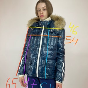 Puede incluir: Una chaqueta acolchada azul con una cremallera blanca y ribetes blancos. La chaqueta tiene una capucha forrada de piel y un bolsillo con cremallera en el lado izquierdo. La chaqueta mide 165 cm de largo, 117 cm de ancho y 137 cm de longitud de manga.