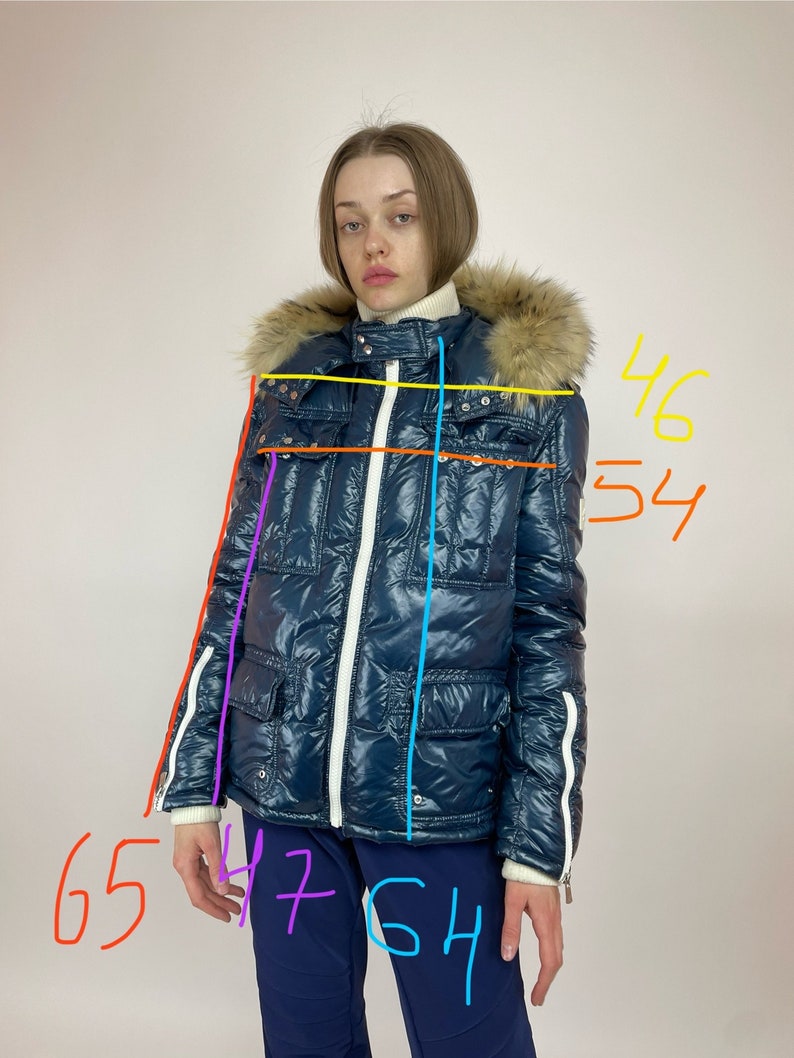 Puede incluir: Una chaqueta acolchada azul con una cremallera blanca y ribetes blancos. La chaqueta tiene una capucha forrada de piel y un bolsillo con cremallera en el lado izquierdo. La chaqueta mide 165 cm de largo, 117 cm de ancho y 137 cm de longitud de manga.