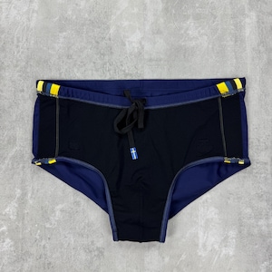 May include: Black and navy blue swim briefs with yellow and blue accents on the waistband. The briefs have a drawstring closure and a small logo detail. The swimwear is designed for swimming and water activities.