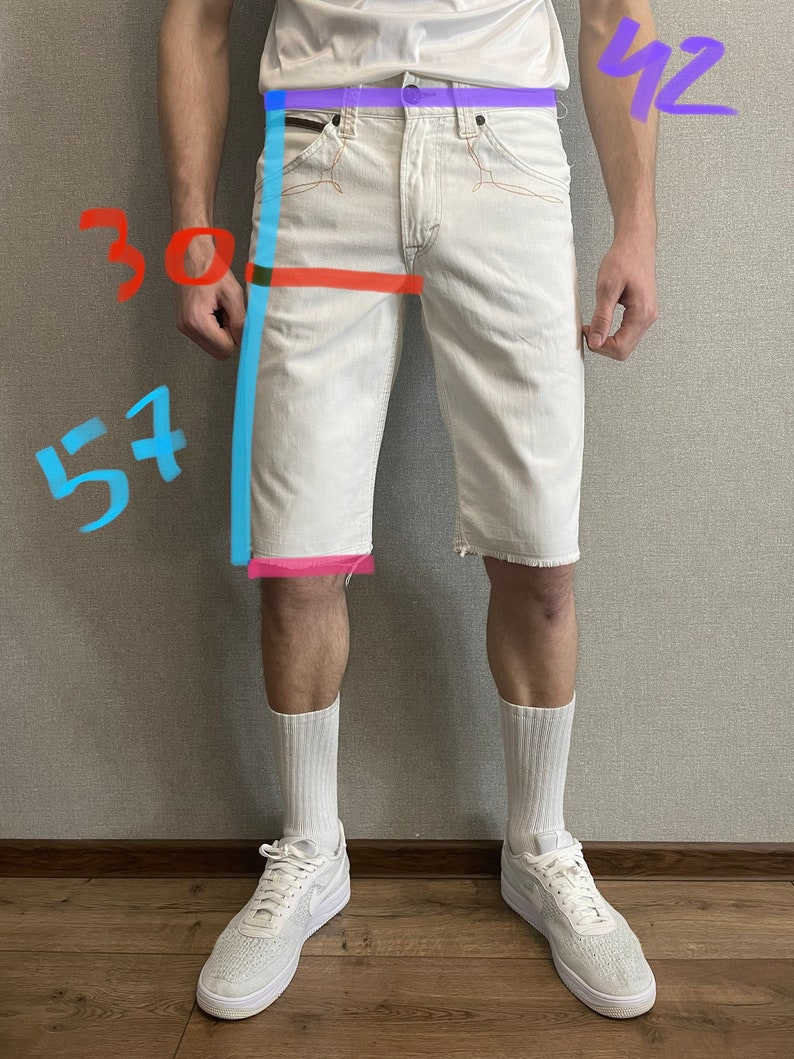 May include: White denim shorts with a frayed hem. The shorts have a 30 inch waist and a 57 inch inseam. The shorts are being worn by a person with white socks and white sneakers.