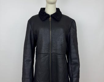May include: Black leather jacket with a black faux fur collar, cuffs, and trim. The jacket has a full-length zipper and is displayed on a mannequin. The jacket is a mid-length coat.