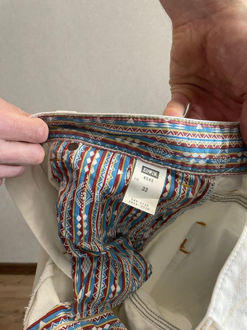 May include: White denim jeans with a patterned inner lining. The label reads "EDWIN 4545 SIZE 32 EXV-2130 E634-2310".