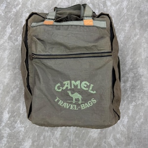 May include: Olive green travel bag with black zippers and the text "CAMEL TRAVEL-BAGS" in green. The bag has a top handle and a front pocket. The bag is made of a lightweight, possibly nylon material.