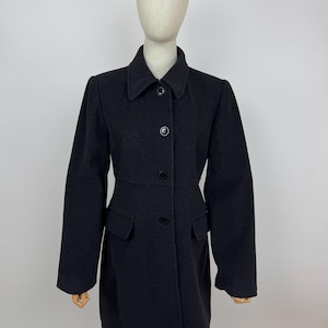 May include: A dark grey wool coat with a classic design. The coat features a notched collar, three buttons down the front, and two front pockets. The coat is displayed on a mannequin.