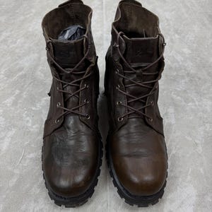 May include: A pair of brown leather work boots with a lace-up design. The boots have a rugged, worn appearance, with visible stitching and a thick, textured sole. The boots are a classic style, suitable for various outdoor activities.