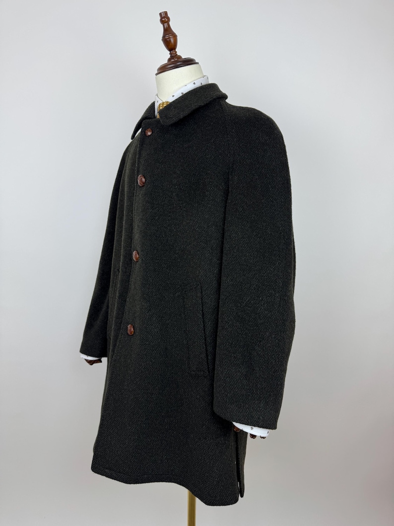May include: A dark green wool coat with a classic design. The coat features a notched collar, three brown buttons, and two front pockets. The sleeves have white cuffs. The coat is displayed on a mannequin.