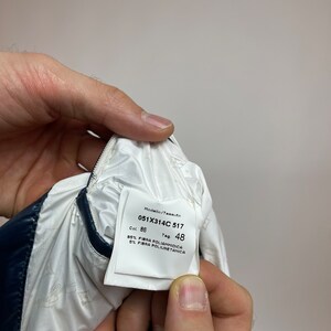 Puede incluir: Etiqueta blanca con texto negro, que muestra el n&uacute;mero de modelo 051X314C 517, el color 86 y la talla de la etiqueta 48. La etiqueta tambi&eacute;n indica la composici&oacute;n de la tela como 95% poliamida y 5% poliuretano.