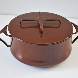 May include: A brown enamel pot with a matching lid. The pot has two curved handles and a handle on the lid. The cookware is a warm, earthy brown color and appears to be vintage.