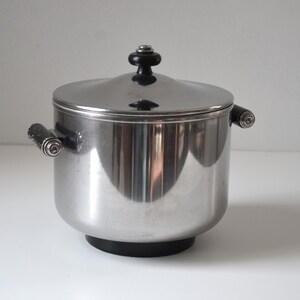 May include: A silver ice bucket with a black lid and handles. The bucket has a black base.