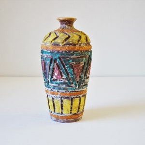 May include: A small, colorful ceramic vase with a geometric pattern. The vase is decorated with yellow, orange, green, and red paint.