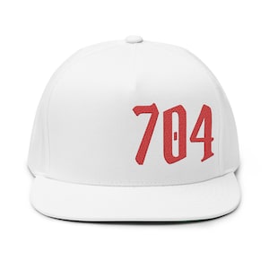 May include: White flat-peak cap featuring the number "704" embroidered in red. The cap has a structured fit and a green underside of the peak.
