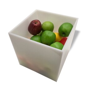 May include: A white square container filled with a variety of fresh fruit, including red apples, green apples, and a yellow lemon.
