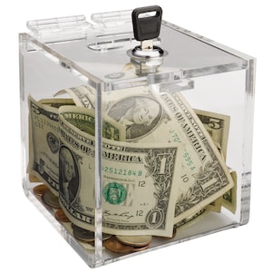 May include: A clear acrylic donation box with a lock and key. The box is filled with US dollar bills and coins.