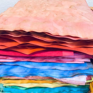 May include: A stack of handmade paper in various shades of pink, orange, blue, green, and yellow. The paper is layered and textured, creating a unique and artistic look.