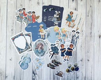 May include: A collection of vintage-style paper ephemera, including stickers and tags. The designs feature illustrations of children, women, and fashion items in shades of blue, white, and brown. Some pieces have text like "Fashion" and "Lady in Blue."