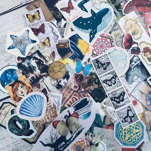 May include: A collection of colorful vintage-style stickers featuring butterflies, flowers, a whale, a seashell, a star, and other designs. The stickers are on a white wooden surface.
