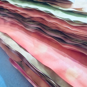 May include: A stack of paper in various shades of pink and green. The paper is folded and layered, creating a textured and colorful effect.