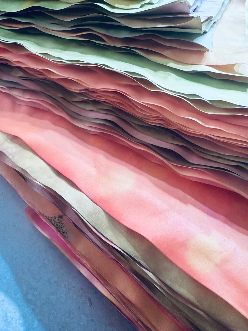 May include: A stack of paper in various shades of pink and green. The paper is folded and layered, creating a textured and colorful effect.