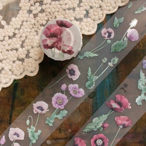 May include: Two rolls of washi tape with a floral design. The tape features pink and purple poppy flowers with green leaves on a translucent background. The text on the tape reads "香 色" and "子" in Japanese.