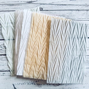 May include: Four sheets of decorative tissue paper with a chevron pattern. The tissue paper is in shades of white, gray, and beige.