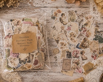 Puede incluir: Una colección de pegatinas de papel estilo vintage con ilustraciones de querubines, flores, mariposas, relojes y texto. Un conjunto está en una bolsa de plástico transparente con una etiqueta marrón que dice Random Sticker Pack Mystery Pack Stickers.