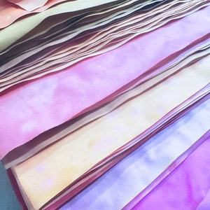 May include: A stack of colorful paper sheets in shades of pink, yellow, and orange. The paper is layered and folded, creating a textured and abstract pattern.